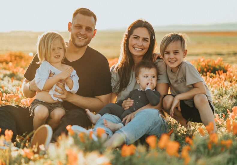 3 women and 2 men sitting on green grass field during daytime