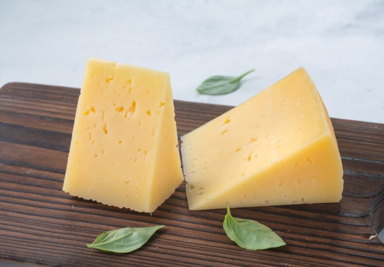 a couple of pieces of cheese sitting on top of a wooden cutting board