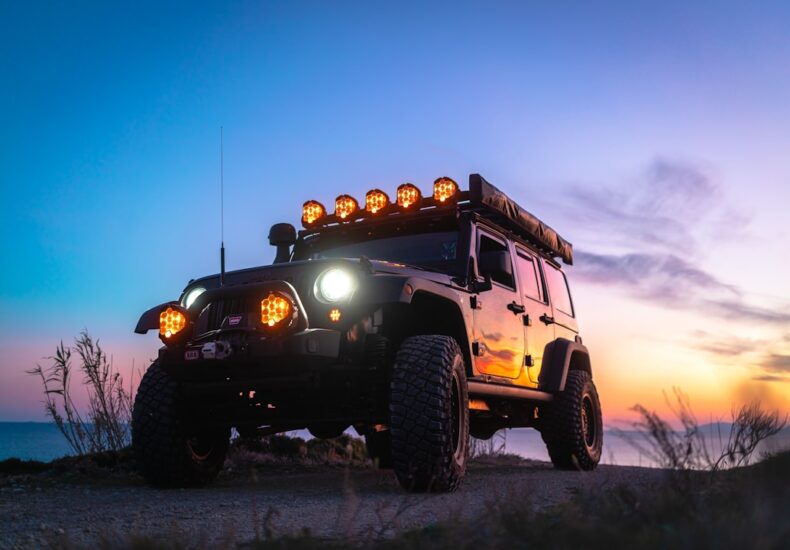 a jeep with lights on is parked on the side of the road