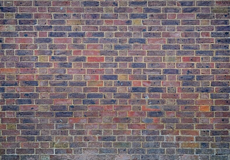 a man sitting on a bench in front of a brick wall