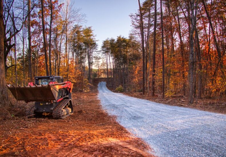 Skid steer loader on a gravel road in autumn forest