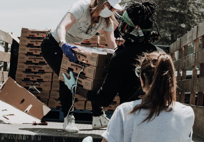 woman in white t-shirt and blue denim jeans sitting on brown cardboard box