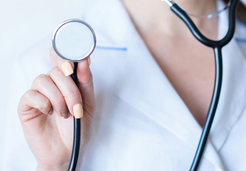 a woman in a white shirt holding a stethoscope