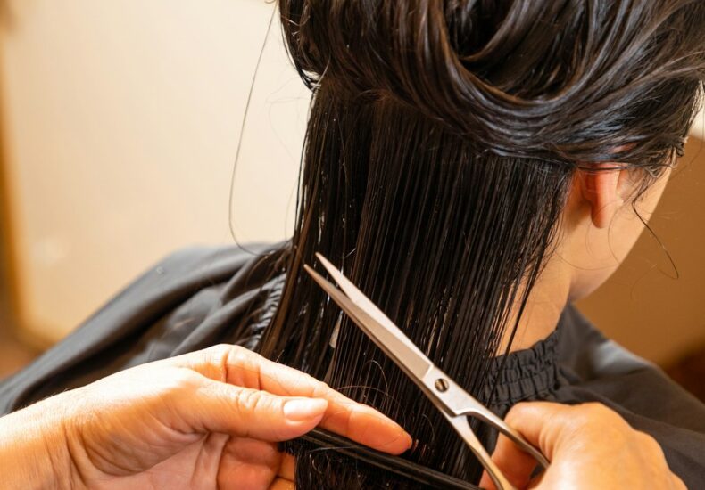 a woman cutting another woman's hair with scissors