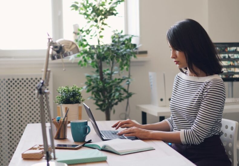 a woman sitting at a desk using a laptop computer