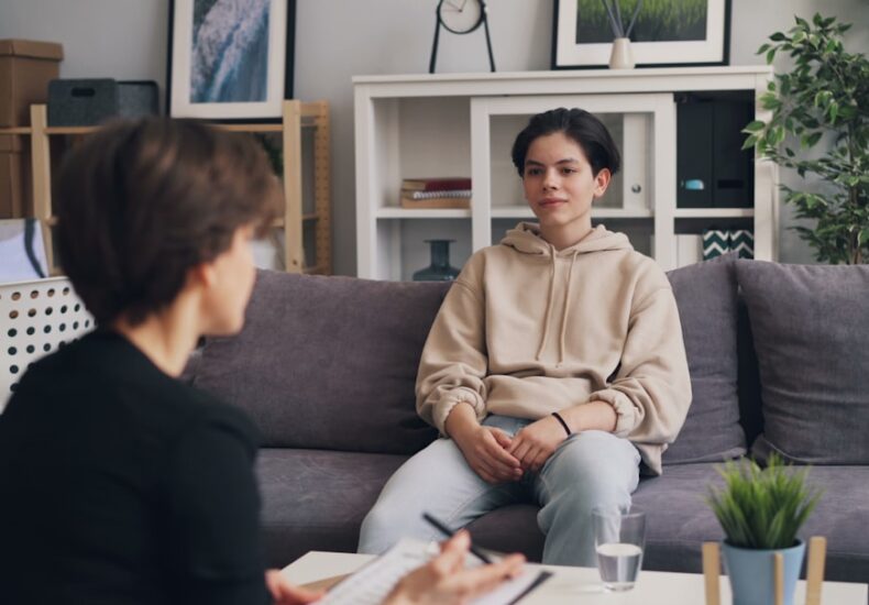 a woman sitting on a couch talking to another woman