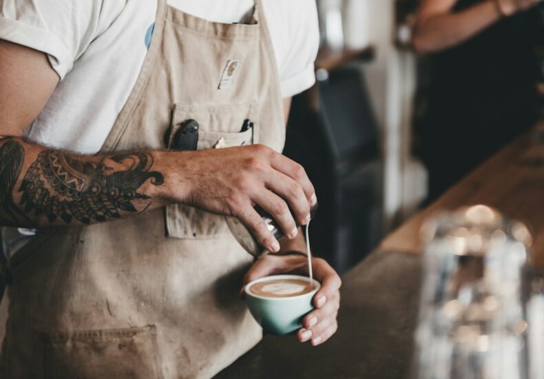 man pouring latte on coffee