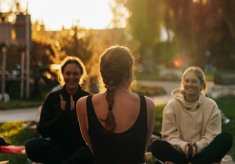 a group of people sitting on top of a lush green field