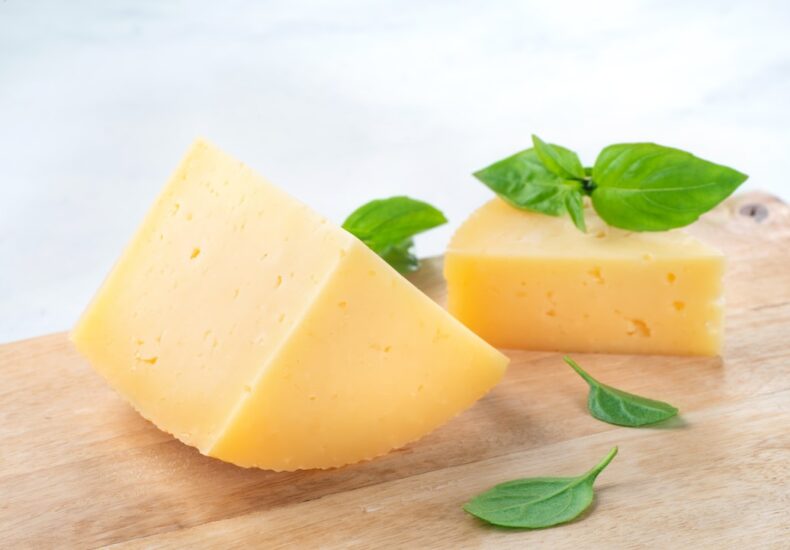 a piece of cheese with a leaf on top of it