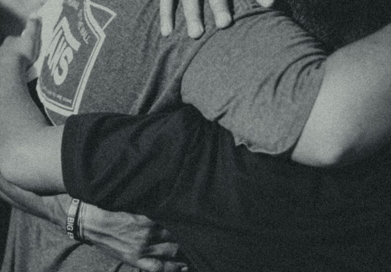 grayscale photography of men doing group hug