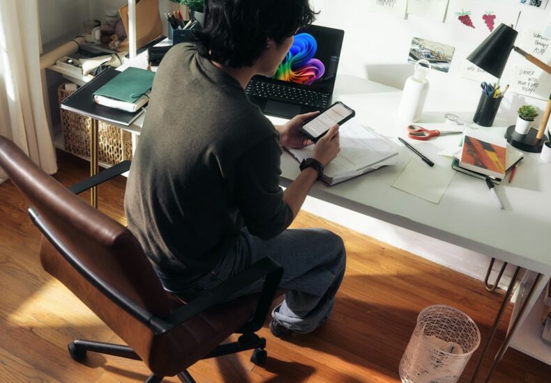 Man working at desk with laptop and phone.