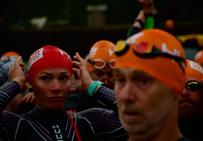 Swimmers in orange and red caps preparing for race.