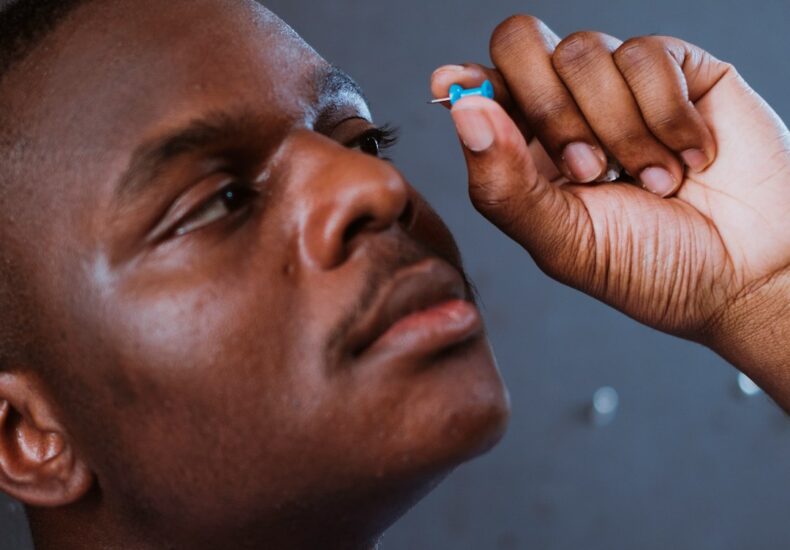 man in blue shirt holding his face