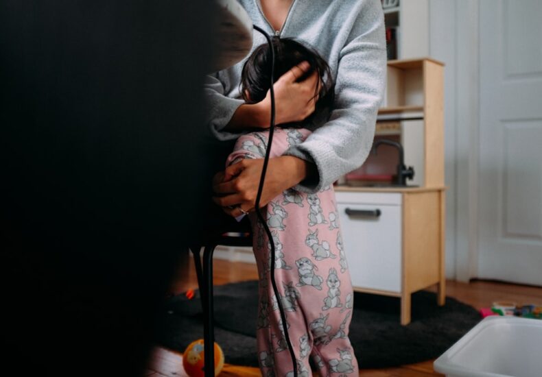 woman in gray cardigan and pink floral dress holding black coated wire