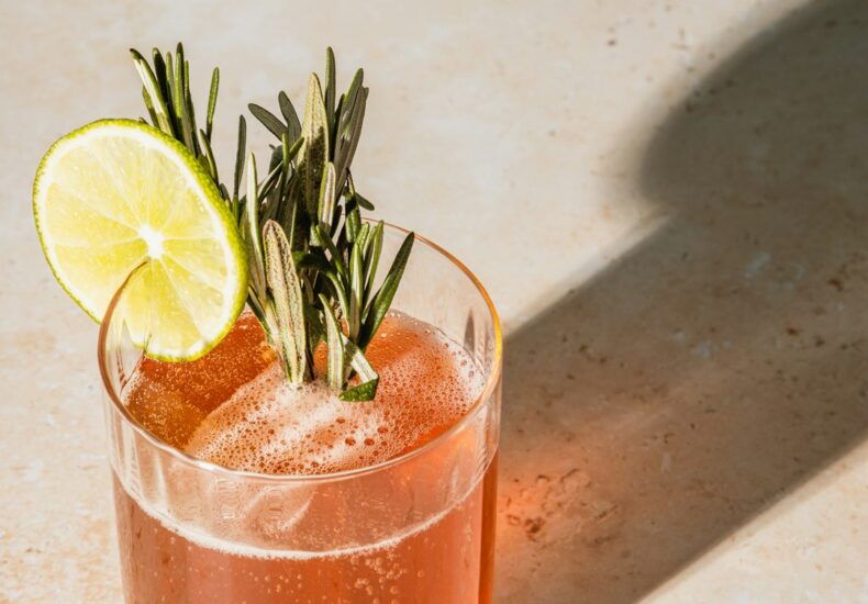 cocktail with lime and rosemary garnish