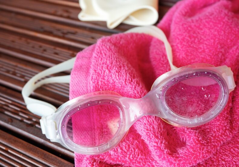 Swim goggles, towel, and a swim cap are displayed.
