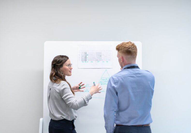 two colleagues discussing ideas at whiteboard