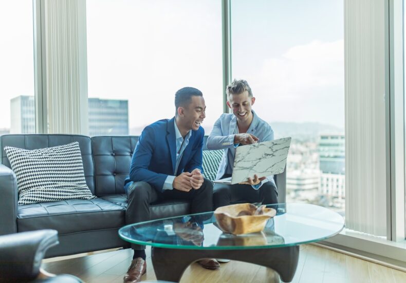 two men in suit sitting on sofa
