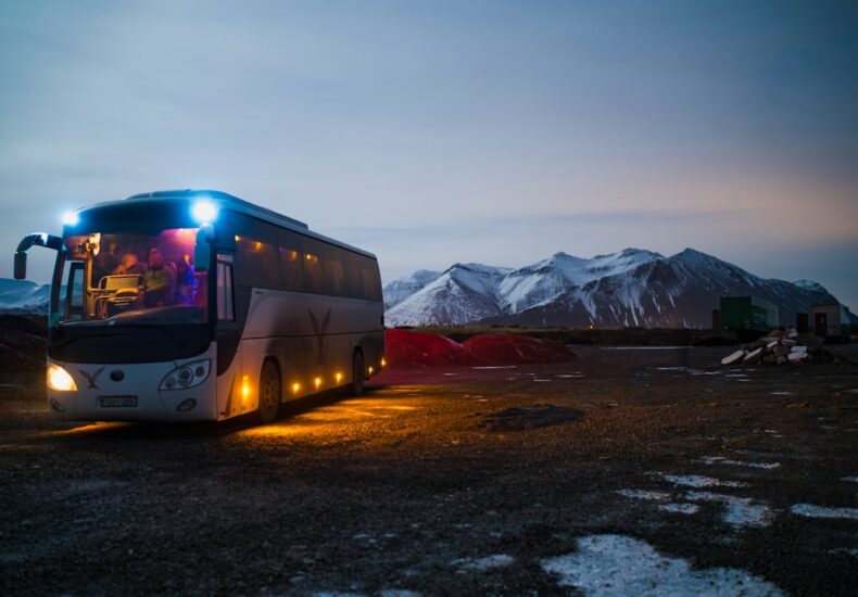 white and black bus running near the mountain