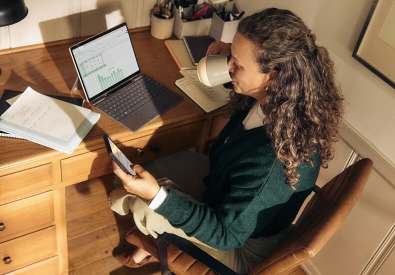 Woman working at a desk with laptop and tablet.