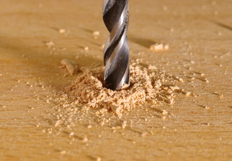 a drill being used to drill a piece of wood