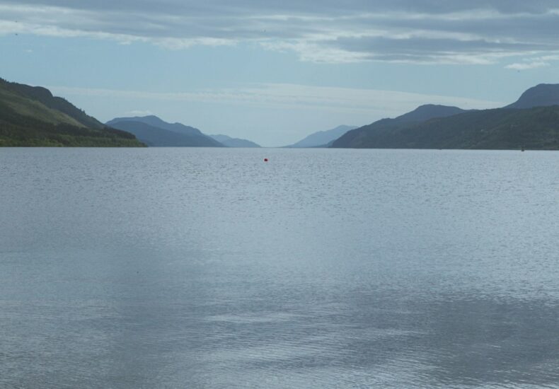 Red buoy on a calm loch with distant mountains