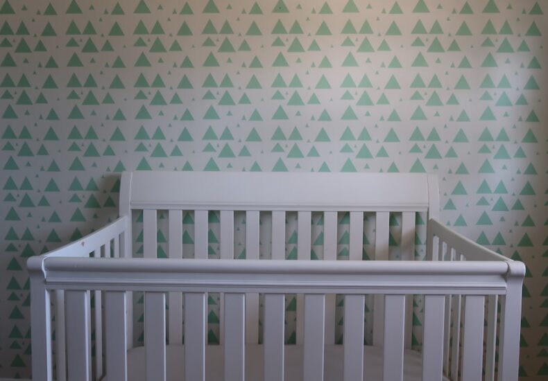 white wooden crib with white and blue polka dot wall