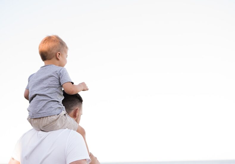 man in white shirt carrying boy