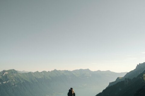 person hiking above mountain overlooking river