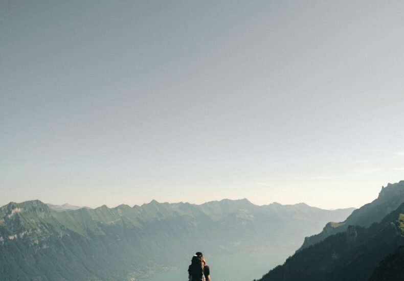 person hiking above mountain overlooking river