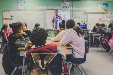 students in classroom with teacher presenting
