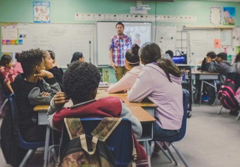 students in classroom with teacher presenting