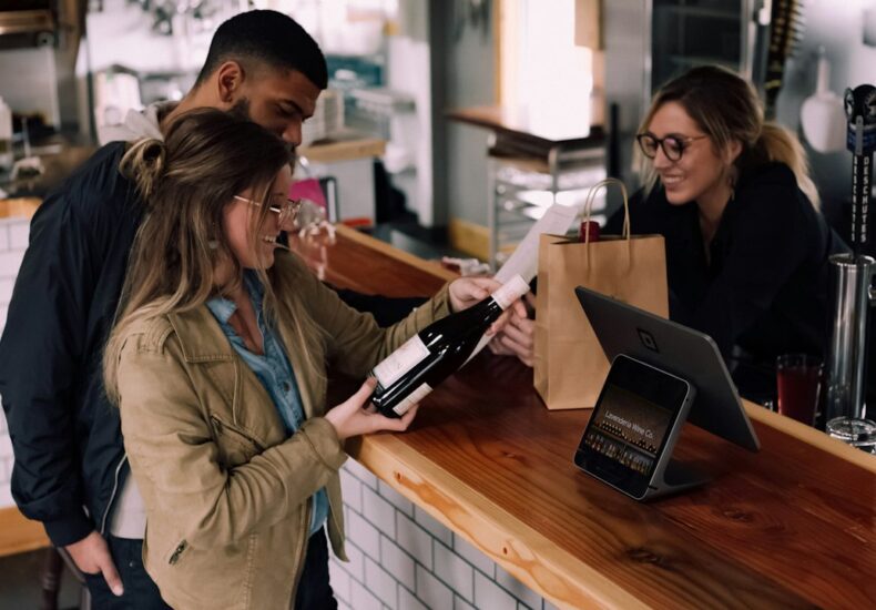 woman holding wine bottle beside man in front of woman smiling