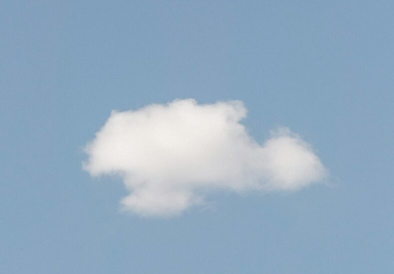 A single white cloud floats in a clear blue sky