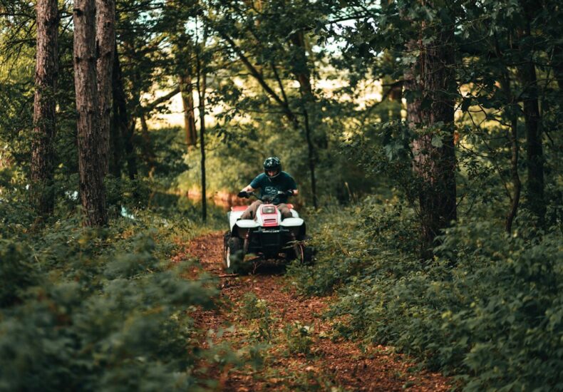 man and woman riding on black and white motorcycle in forest during daytime
