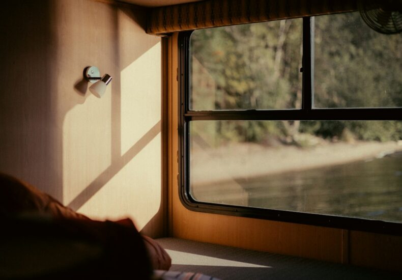 Sunlight streams into a camper window overlooking a lake